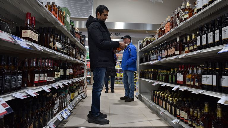 Gopal TG of Halifax, stands between American-made spirits on the left and Canadian-made on the right, during a visit to an NSLC store in Halifax, Nova Scotia, Canada February 3, 2025. REUTERS/Ingrid Bulmer