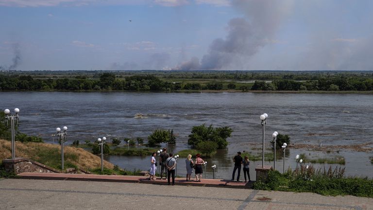 Local residents stand on an embankment of the Dnipro river which flooded after the Nova Kakhovka dam breached as smoke rises after shelling on the opposite bank, amid Russia's attack on Ukraine, in Kherson, Ukraine June 6, 2023. REUTERS/Ivan Antypenko