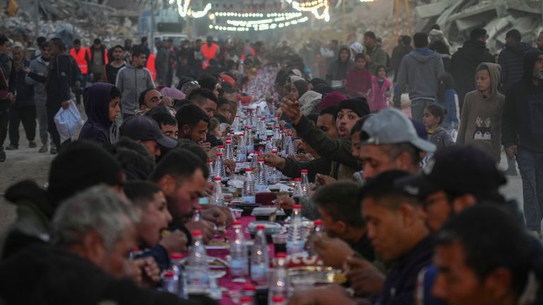 Palestinians sit at a large table surrounded by the rubble of destroyed homes and buildings as they gather for iftar, the fast-breaking meal, on the first day of Ramadan in Rafah, southern Gaza Strip, Saturday, March 1, 2025 (AP Photo/Abdel Kareem Hana)
