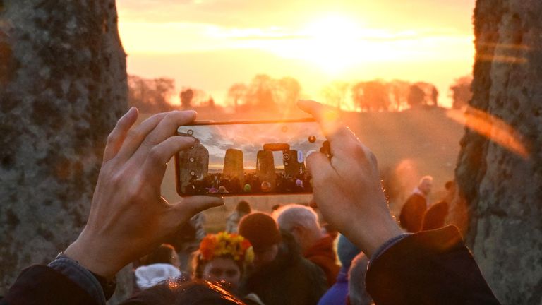 A person takes a picture as revellers attend spring equinox celebrations during sunrise at Stonehenge stone circle, near Amesbury, Britain, March 20, 2025. REUTERS/Jaimi Joy