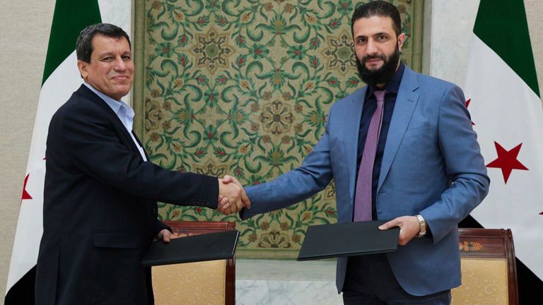 In this photo released by Syrian state news agency SANA, Syria's interim President Ahmad al-Sharaa, right, shakes hands with Mazloum Abdi, the commander of the U.S.-backed Kurdish-led Syrian Democratic Forces, in Damascus, Syria, Monday, March 10, 2025. (SANA via AP)