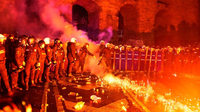 A police officer kicks a flare thrown by protesters during clashes in a rally against the arrest of Istanbul's Mayor Ekrem Imamoglu, in Istanbul, Turkey, Friday, March 21, 2025. (AP Photo/Khalil Hamra)