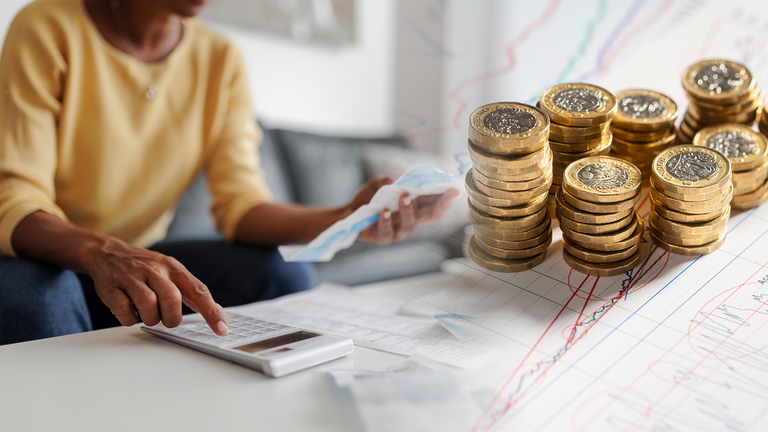 Picture of person looking at bills with calculator and pound