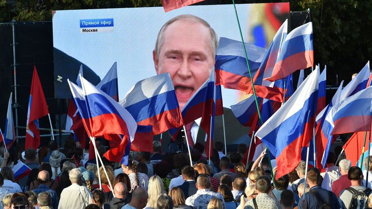 FILE - People watch as Russian President Vladimir Putin delivers a speech after signing treaties for four regions of Ukraine to join Russia in the Moscow's Kremlin, during a meeting in Sevastopol, Crimea, on Sept. 30, 2022. (AP Photo, File)