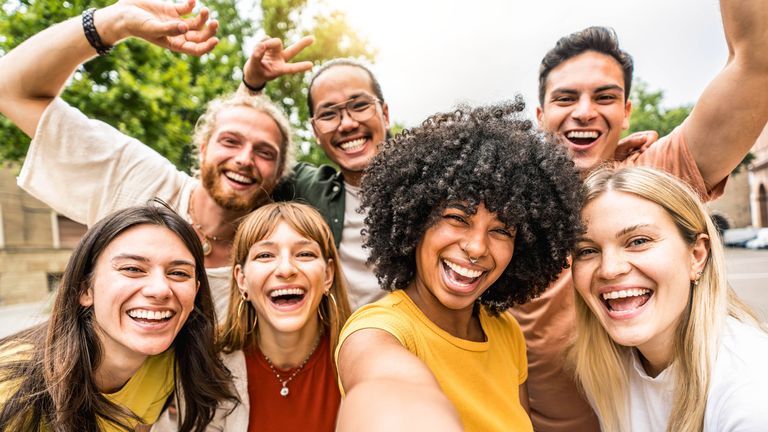 Multicultural friends smiling at camera together outside - Happy young people taking selfie with smart mobile phone device walking on city street - Youth community and technology concept