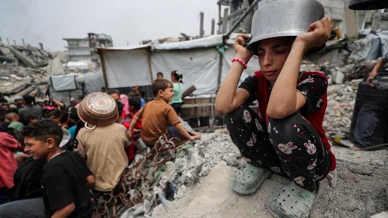 A girl waits with other Palestinians to receive food cooked by a charity kitchen in Beit Lahia, northern Gaza Strip.  Pic: Reuters/Mahmoud Issa