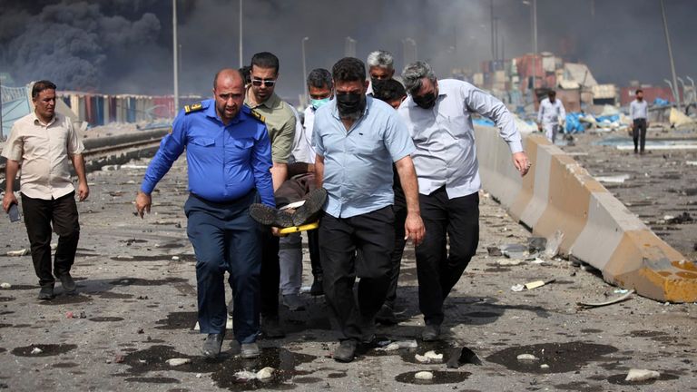 Men carry an injured man through debris after the explosion at Rajaei port. Pic: AP