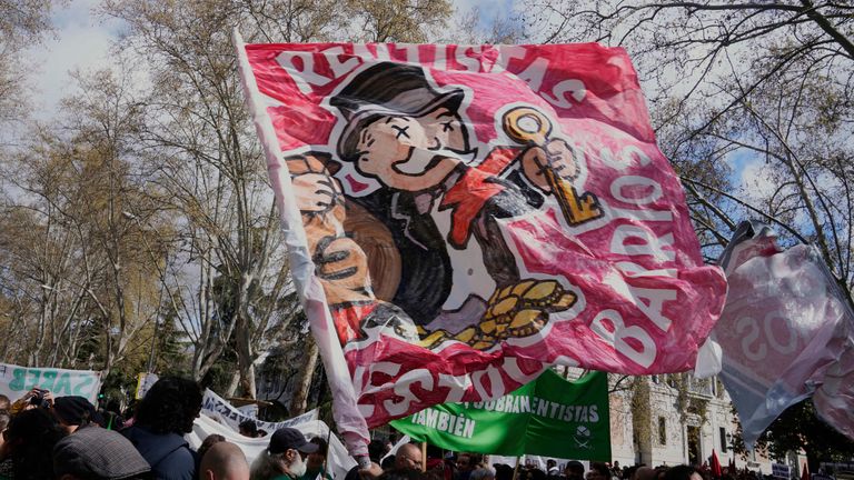 People march with a flag depicting a rich banker during a demonstration to protest high housing costs in Madrid, Spain, Saturday April 5, 2025. (AP Photo/Paul White)