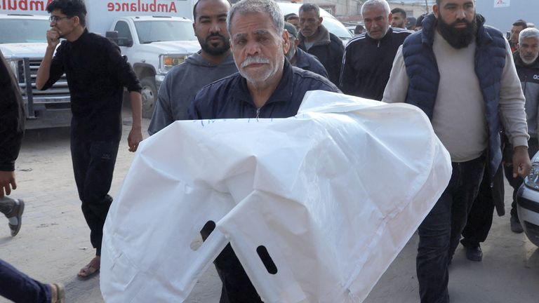 A man carries the body of a Palestinian killed in Israeli strikes, at Nasser hospital, in Khan Younis, in the southern Gaza StriP