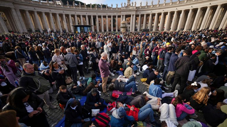 People rest on the ground ahead of the funeral of Pope Francis in St Peter's Square at the Vatican. Pic: AP
