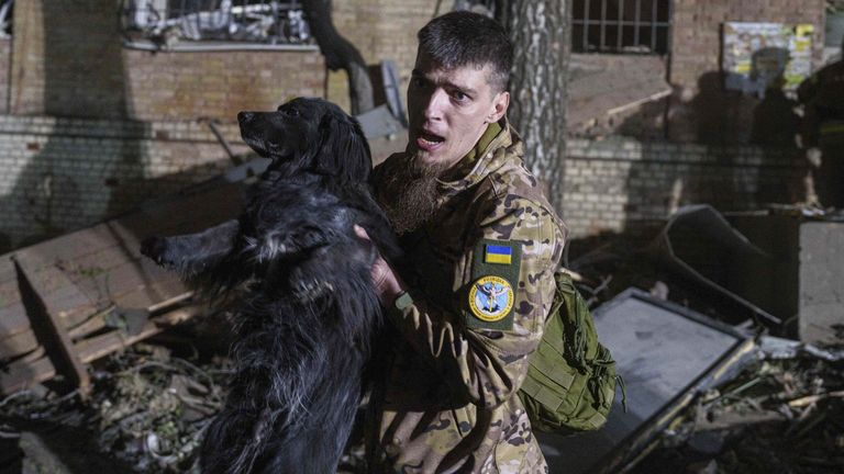 A Ukrainian serviceman carries a dog out of a house damaged by a Russian airstrike in a residential neighborhood in Kyiv, Ukraine, on Thursday, April 24, 2025. (AP Photo/Evgeniy Maloletka)