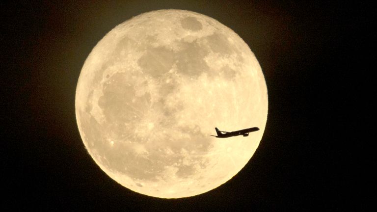 An airplane flies past the full moon, also known as the Flower Moon, rising over Los Angeles, Monday, May 12, 2025. (Ringo Chiu via AP)