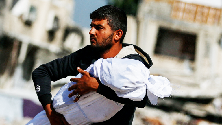 A Palestinian man carries the body of a child killed in Israeli strikes,‏ in Jabalia, in the northern Gaza Strip May 16, 2025. REUTERS/Mahmoud Issa TPX IMAGES OF THE DAY