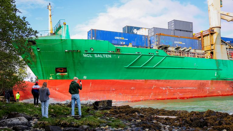 People stand near a container ship, which almost hit a house, in Trondheim, Norway, May 22, 2025. NTB/Jan Langhaug/via REUTERS ATTENTION EDITORS - THIS IMAGE WAS PROVIDED BY A THIRD PARTY. NORWAY OUT. NO COMMERCIAL OR EDITORIAL SALES IN NORWAY.
