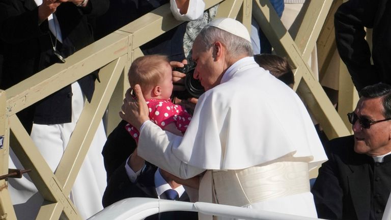 Pope Leo XIV is handed a baby as he makes his way to the inaugural mass. Pic: AP