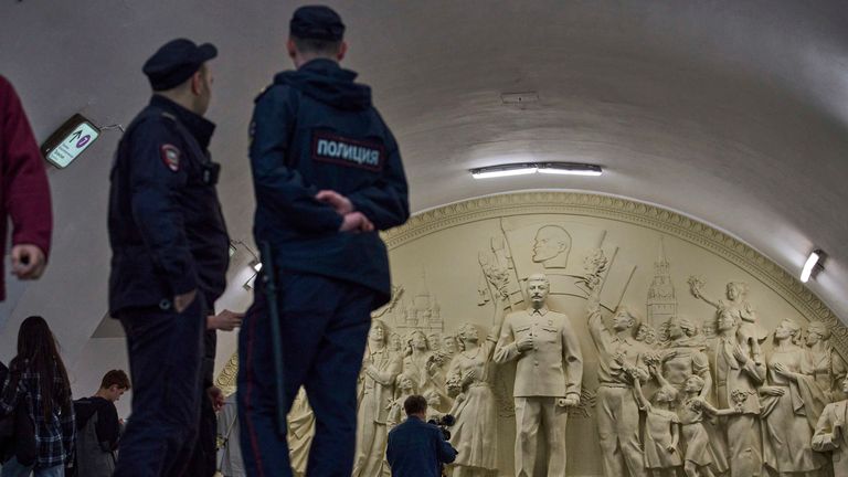 Police officers stand in front of the statue showing the former Soviet Union leader.  Pic: AP/Alexander Zemlianichenko