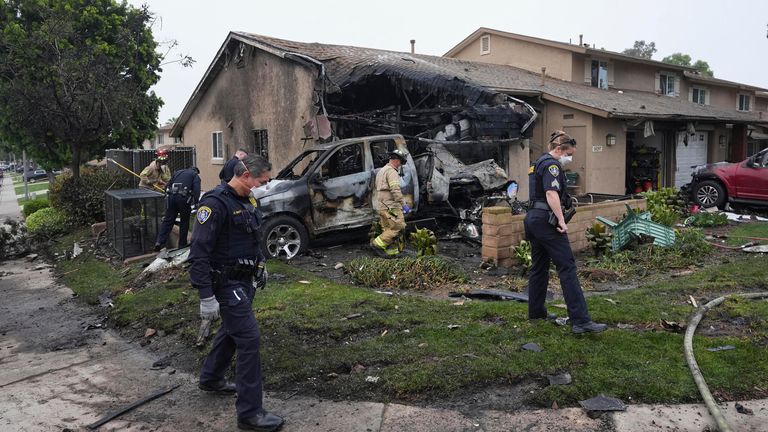 Authorities work the scene where a small plane crashed into a San Diego neighborhood, setting several homes on fire and forcing evacuations along several blocks early Thursday, May 22, 2025. (AP Photo/Gregory Bull)