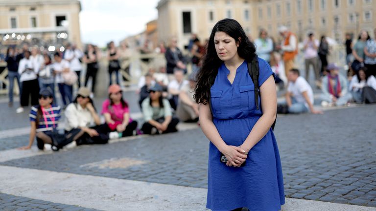 A woman kneels at St. Peter's Square, on the first day of the conclave to elect the new pope, at the Vatican, May 7, 2025. REUTERS/Eloisa Lopez