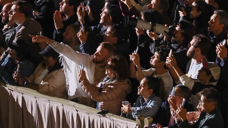 Faithful react to black smoke rising from the chimney on the Sistine Chapel indicating no decision has been made to elect a new pope, at the Vatican, May 7, 2025. REUTERS/Claudia Greco